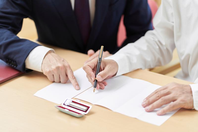 Hombre de traje señala algo en un documento a otro